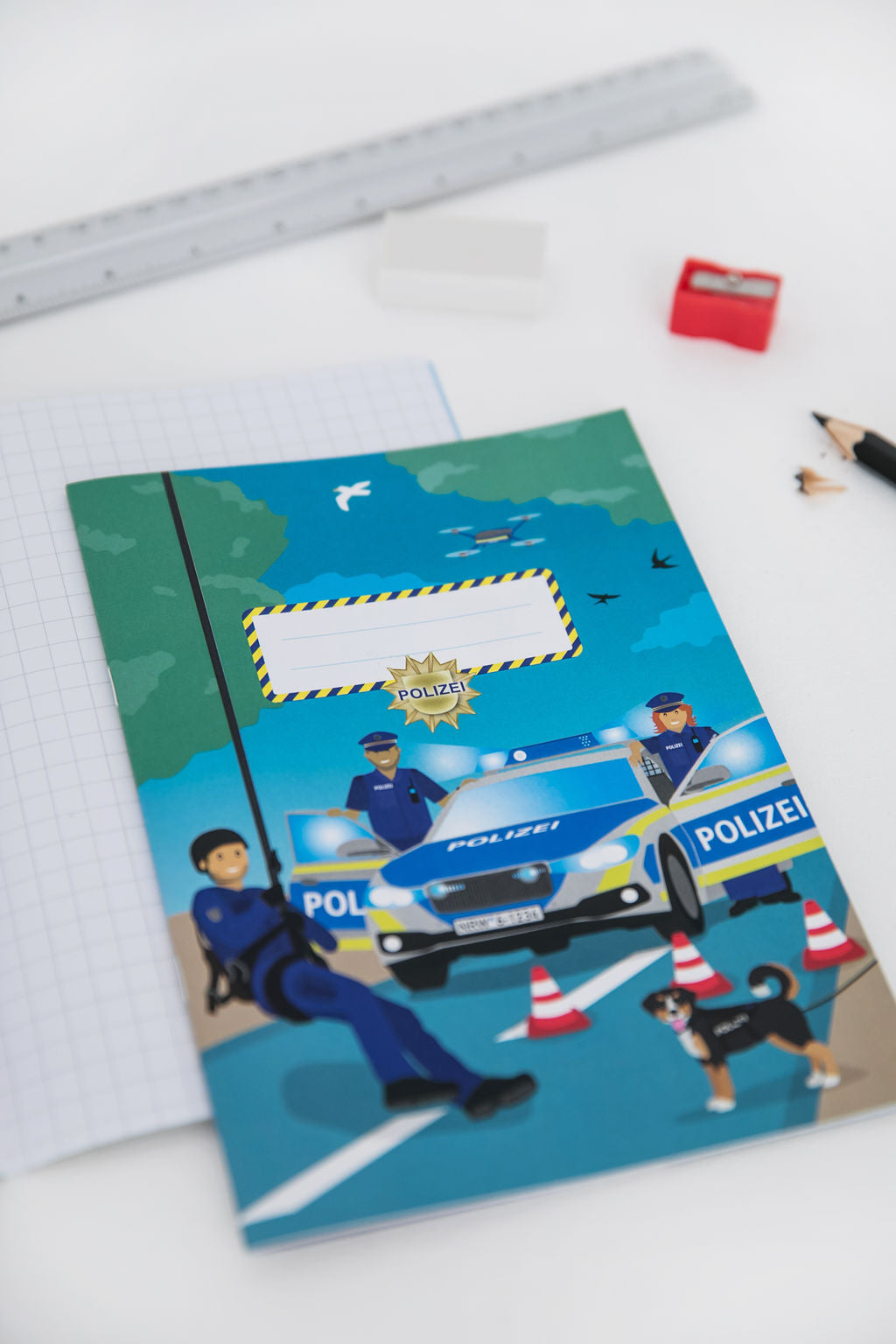 Blaues Polizei-Schreibheft A5 für die erste Klasse mit Lineatur 1 und Polizisten-Motiv.