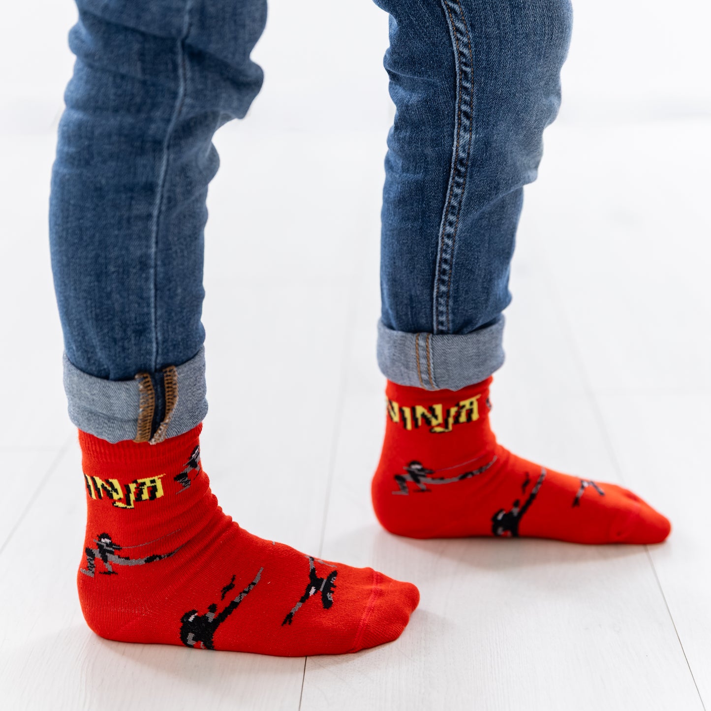 Ein Kind trägt die roten Socken mit schwarzen Ninja-Motiven.