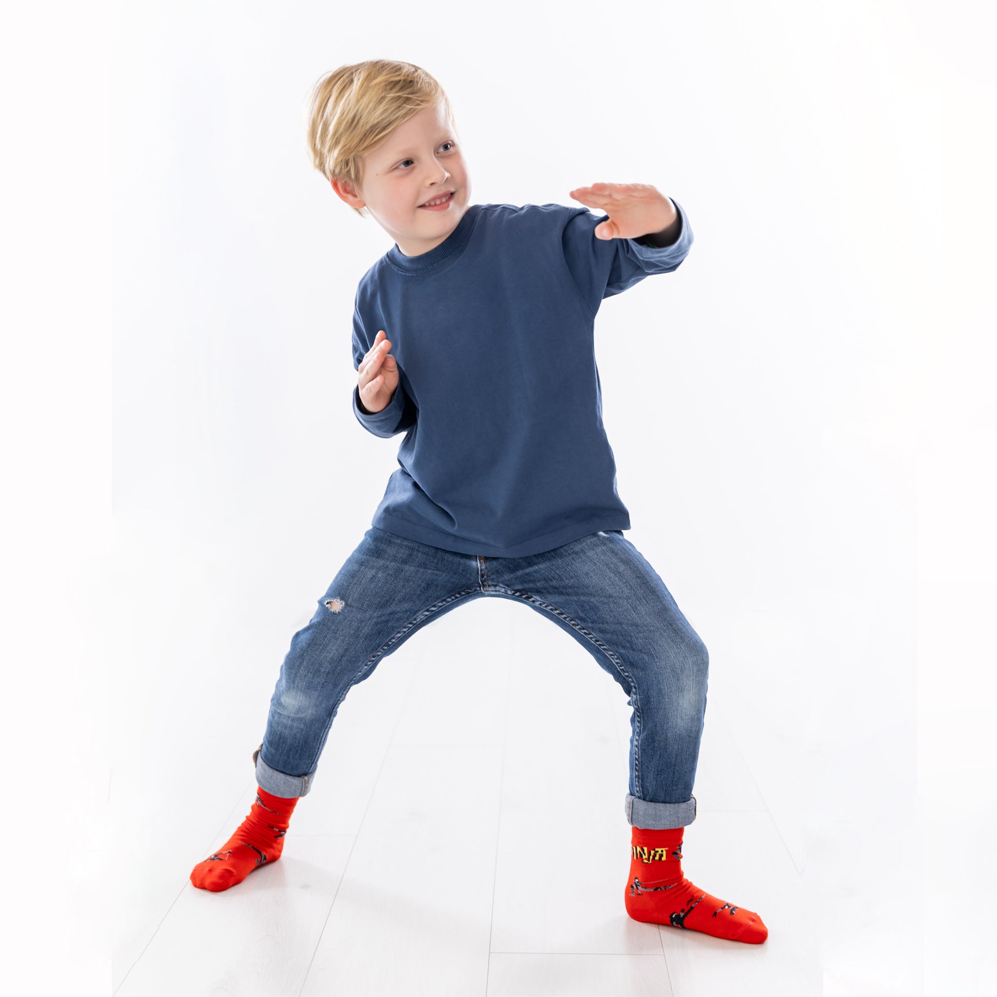 Kind in Action mit den roten Ninja-Motivsocken beim Verkleiden oder Spielen.