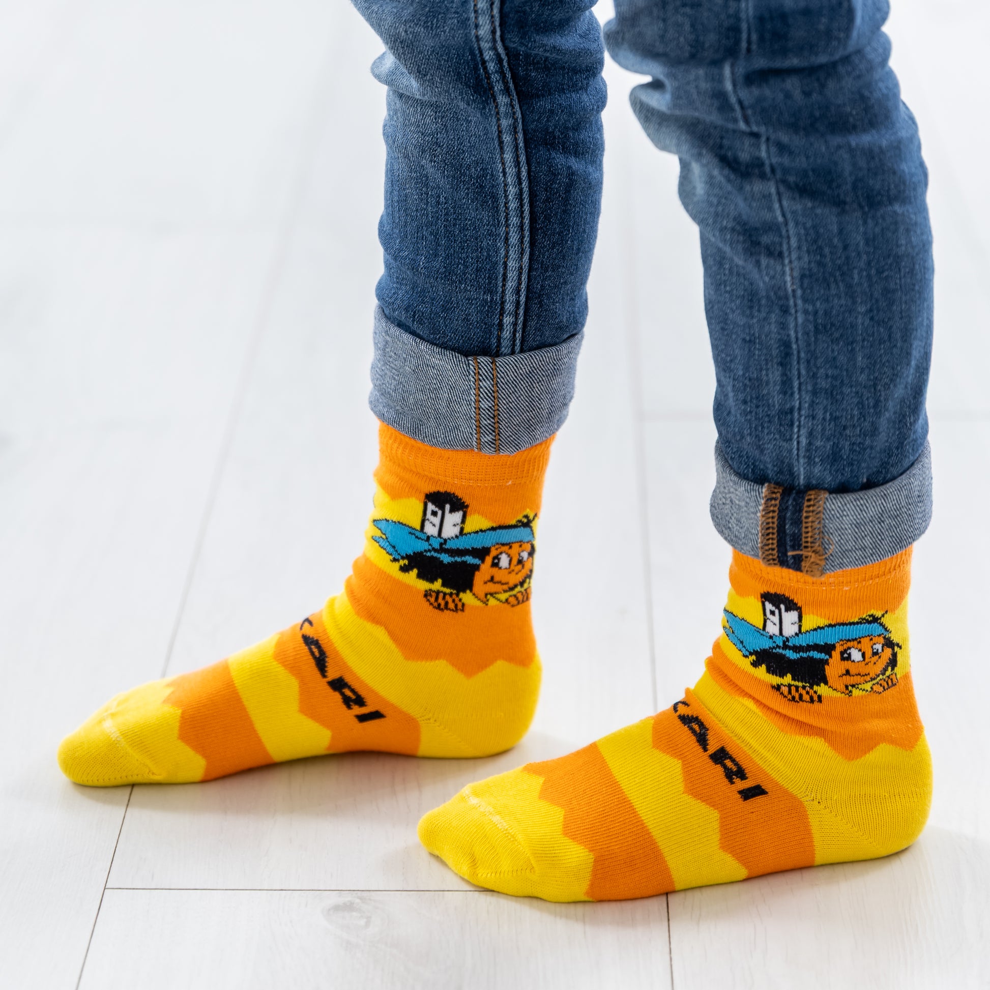 Ein Kind trägt die gelb-orange gestreiften Yakari Socken.