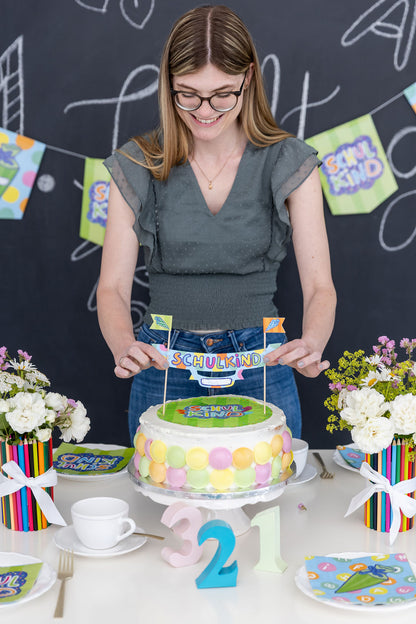 Farbenfrohe Tischdekoration mit Kuchen und Tortenbanner für die Einschulgungsfeier.