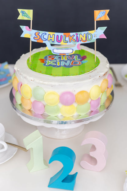 Buntes Tortenbanner zur Einschulung als festliche Dekoration auf einer Torte.