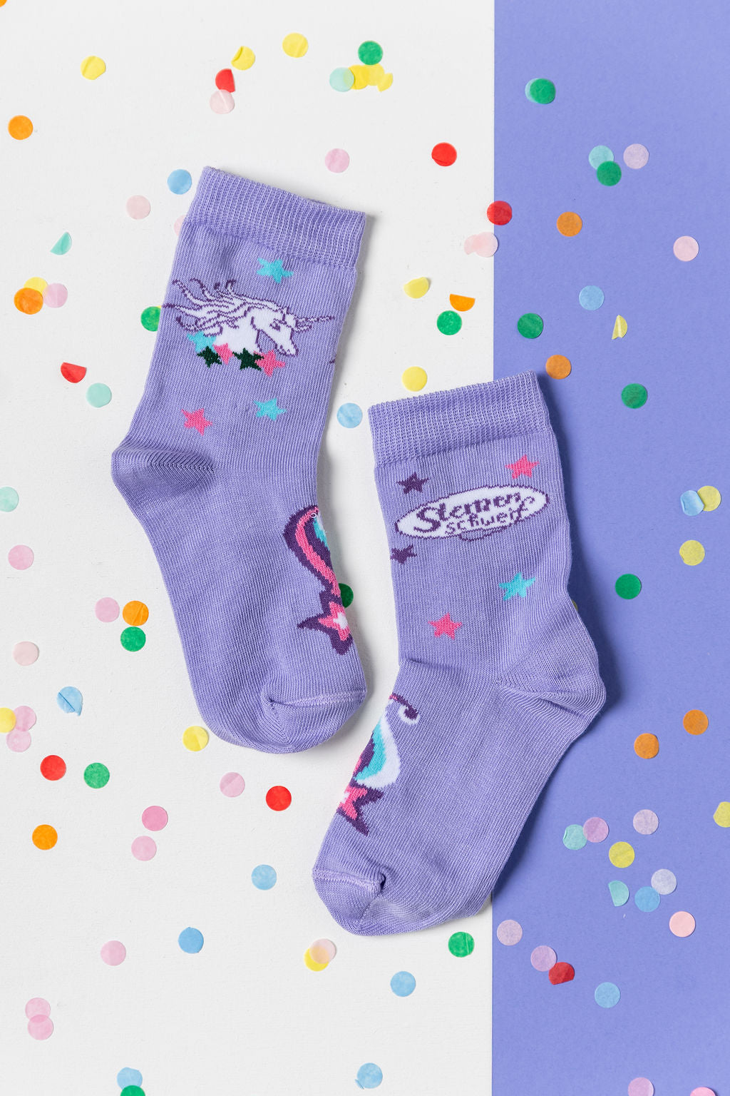Lila Sternenschweif Kindersocken mit Einhorn-Motiv und bunten Sternen auf Konfetti-Hintergrund.