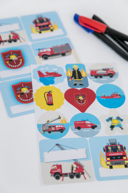 Zwei A5-Stickerbögen mit acht weißen Namensfeldern zum Beschriften und neun bunten Motivstickern mit Feuerwehrautos, Löschflugzeug und Feuerwehrmann.